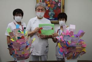メッセージカードとメッセージの花束に囲まれた伊藤理事長（中央）と看護部長（右）ら