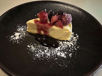 赤いフルーツとソースが乗ったチーズケーキの写真
