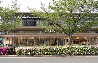 店頭の写真街路樹の緑、ツツジが咲いている